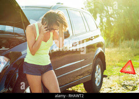 Frau mit einem schwarzen Auto, die unten auf der Straße brach. Die telefonische Hilfe bei der kaputten Auto zu erhalten. Stockfoto