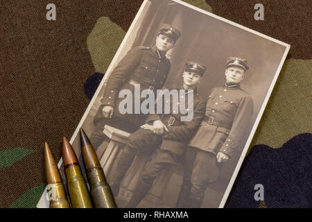 Postkarte von drei lettische Soldaten in der Zeit um 1935 und Gewehrkugeln auf Trenchcoat Stockfoto