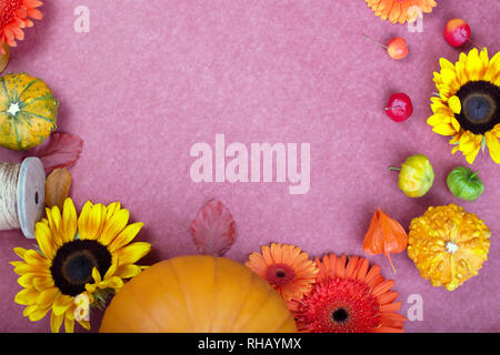 Ansicht von oben in gelb und orange Blumen, Seil, Haspel und Kürbisse auf rosa Hintergrund. Leere Grußkarte für kreative Arbeit Design. Flach Stockfoto