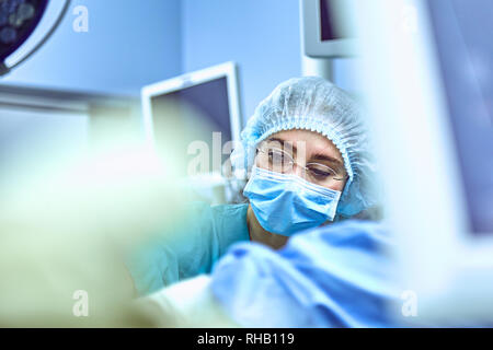 Junge weibliche Chirurg mit medizinischen Team zurück auf die Chirurgie Stockfoto