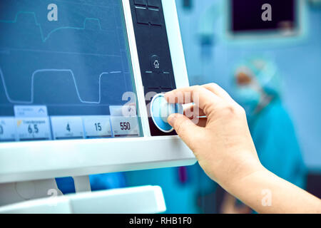 Die Überwachung der Vitalparameter des Patienten im Operationssaal. Arzt bei der Vitalparameter des Patienten cheking. Elektrokardiogramm Monitor während der Operation in Betrieb. Stockfoto