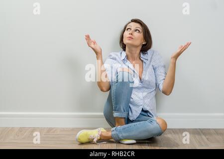 In der Nähe von erwachsenen Frau um die Frage über leere Kopie Raum weiße Wand im Hintergrund sitzen Denken. Stockfoto