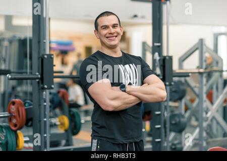 Portrait von muskulös Sportlich lächelnden Mann in der Turnhalle, stattlich Professionelle gym Instructor in die Kamera schaut. Stockfoto