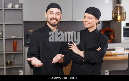 Porträt von zwei zuversichtlich persönliche Köche in der modernen Inneneinrichtung der privaten Küche stehend Stockfoto