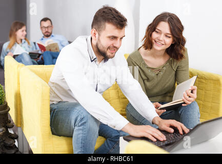 Paar junge Reisende mit Laptop Planung touristische Rundfahrt beim Stillstehen in Hostel Lobby Stockfoto