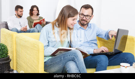 Paar junge Reisende mit Laptop Planung touristische Rundfahrt beim Stillstehen in Hostel Lobby Stockfoto