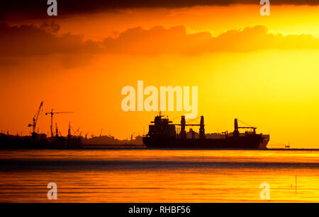 Silhouetten von Kränen und Frachtschiffe Stockfoto