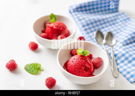 Himbeersorbet in zwei Tassen auf weißen Tisch mit blau serviette Stockfoto