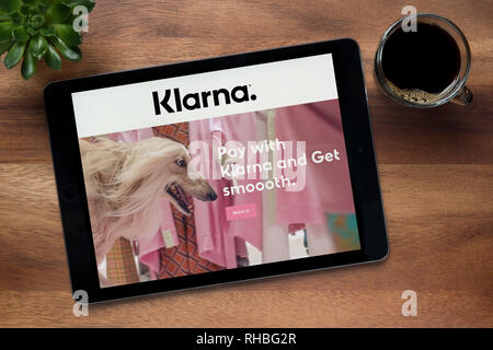 Die Website von Klarna ist auf einem iPad Tablet gesehen, auf einer hölzernen Tisch zusammen mit einem Espresso und einem Haus Anlage (nur redaktionelle Nutzung). Stockfoto