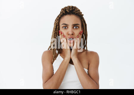 Taille - geschossen von schockiert und beeindruckt betäubt, stilvolle dunkelhäutige Frau mit dreads öffnung öffnung von Empathie und schüttelte Holding Palmen auf Wangen Stockfoto