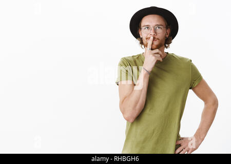 Taille-up Shot des Menschen, zu denken, was er Lust zu essen, chosing Restaurant im Hinterkopf in nachdenkliche hmm Pose als berühren Lippe, Auswahl suchen Stockfoto