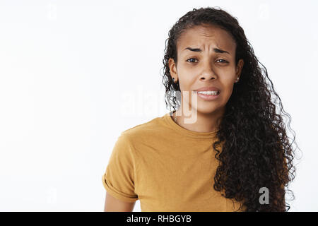 Huch es schlecht. Portrait von besorgt, unbeholfen und ungeschickt ausgedrueckt junge afrikanische amerikanische weibliche Assistant runzelte die Stirn und Aufeinanderpressen der Zähne als schuldig fühlen Stockfoto