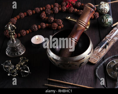 Kupfer Klangschale und einen hölzernen Stock auf einem braunen Tisch, ein Stick mit Weihrauch brennt in der Nähe Stockfoto