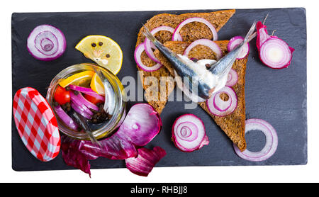 Gebeizt Sprotten in hausgemachten Marinade aus Olivenöl, Essig, Zitronensaft, Meersalz mit Gewürzen, Zwiebeln und Zuckerrüben mit Roggenbrot serviert. Über weiß Bac isoliert Stockfoto