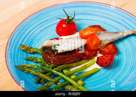 Blauer Wittling Fisch gebacken mit getrockneten Tomaten, Spargel und cremige Knoblauchsauce Stockfoto