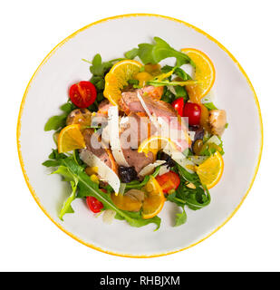 Blick von oben auf die bunten Salat von Ente Filets mit frischem Rucola, Tomaten, Zwiebeln, Schnittkäse, Trockenpflaumen und Orange serviert auf weiße Platte. Isola Stockfoto