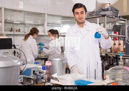 Positive männliche Chemiker im Labor arbeiten, die Analyse von flüssigen Proben in versuchsfläschchen Stockfoto