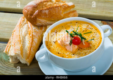 Norwegische Küche. Cremesuppe mit Lachs in Weiß Suppenteller mit Brot auf hölzernen Hintergrund serviert. Stockfoto