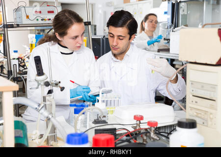 Zwei Studierende der Fakultät für Chemie der Universität Experimente im Labor, die Ergebnisse in der Arbeitsmappe Stockfoto