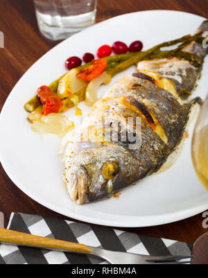 Dorade im Ofen gebacken serviert mit Spargel, Zwiebeln und Tomaten Stockfoto