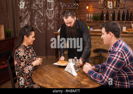 Kellner, das junge Paar mit Croissants. Im schönen Pub Datum. Stockfoto