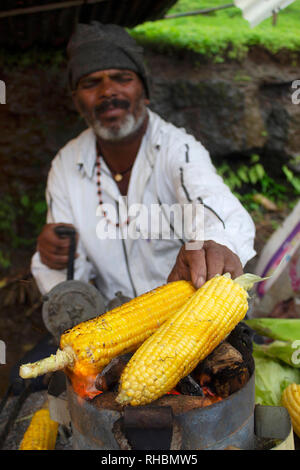 MAHARASHTRA, Indien, August 2018, Verkäufer rösten Maiskolben auf heißen Kohlen Stockfoto