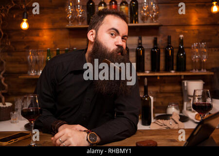 Hübscher junger Barkeeper spielen mit seinem Bart. Große Persönlichkeit. Stockfoto