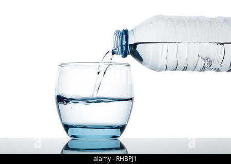 Trinkwasser ist in Glas aus der Flasche ausgegossen Stockfoto