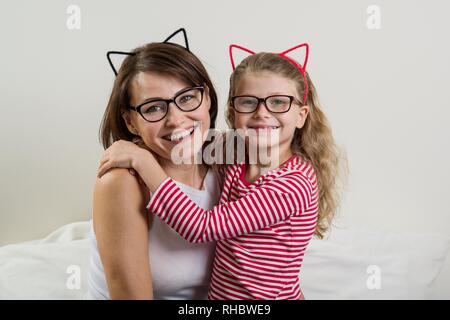 Die Tochter liebevoll umarmt ihre Mutter. Eltern und Kind in Gläsern. Stockfoto