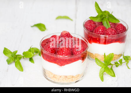 Hausgemachter Käsekuchen mit Himbeeren und Minze im Glas Stockfoto