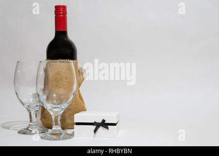 Flasche Rotwein, zwei Weingläser und einen weißen Geschenkbox. Jubiläum. Ihr Geburtstag. Valentines Tag. Stockfoto