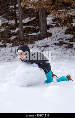 Junge Mädchen bilden ein Schneemann an einem sonnigen Tag im Winter verschneite Wälder in den Bergen. Stockfoto