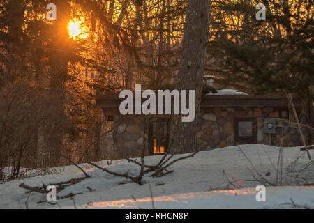 Die aufgehende Sonne beleuchtet einen Stein Kabine in Nordwisconsin. Stockfoto