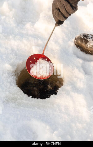 Löschen der Eisfischen Loch mit einem hausgemachten Eis scooper. Stockfoto