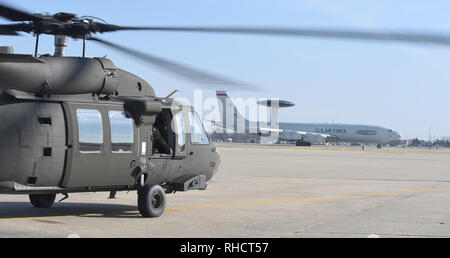 Eine E-3 Sentry Der 552Nd Air Control Wing Linien auf die Startbahn während der Oklahoma Army National Guard M UH-60 Blackhawk Der 1-244 th Aviation Regiment bereitet zum take-off für ein SENTRY REX 08-07 mission Jan. 15, 2019, Tinker Air Force Base, Oklahoma. SENTRY REX 08-07 war ein Multi-service-Übung der Tinker AFB von Jan. 14-18 Fokussierung auf kombinierte Kraft Rettungsaktionen der abgestürzten fliegenden Personals. (U.S. Air Force Foto/Greg L. Davis) Stockfoto