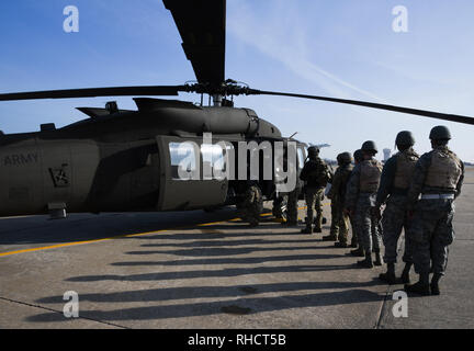 Lange Schatten sind auf der Flucht Line als Mitglieder der 137 Special Operations Wing, Oklahoma Air National Guard, Line-up Board eine der Oklahoma Army National Guard M UH-60 Blackhawk an Tinker Air Force Base, Oklahoma während SENTRY REX 08-07 Übung am Jan. 15, 2019 zu werfen. Das Training erlaubt die spezielle Operatoren in einer verteidigten Landung eingefügt - Zone mit dem Ziel der Rettung einer abgestürzten aircrew Mitglied werden. (U.S. Air Force Foto/Greg L. Davis) Stockfoto