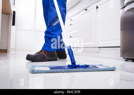 Niedrige Abschnitt eines Mannes Reinigung weißen Marmorboden mit Mop In der Küche Stockfoto