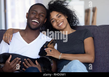 Gerne afrikanische Paar spielen mit Hund sitzt auf der Couch, Porträt Stockfoto