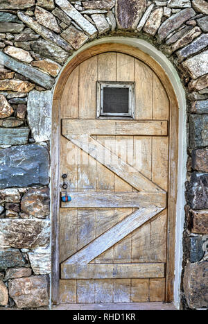 Gewölbten Tür. Außen Holz verwittert Weinkeller Tür mit kleinen Fenster. Stock Bild. Stockfoto