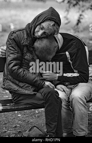 Eine obdachlose Paar kuscheln Sie zusammen, als sie an einem kalten Tag in Planty Park, Krakau, Polen, Europa schlafen. Stockfoto