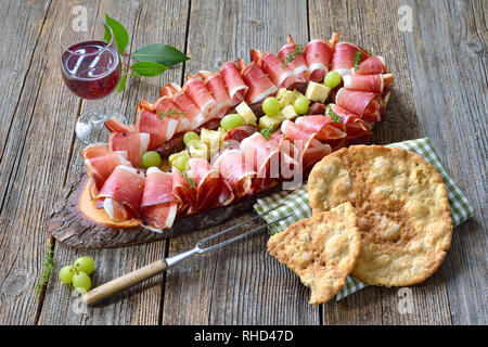 Typische Südtiroler Jause mit Speck, Salami und alter Bergkäse, serviert mit lokalen Rotwein und crunchy Roggen Fladenbrot Stockfoto