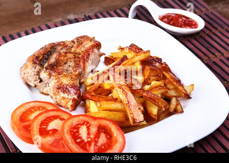 Kostenlose gegrillt - Bereich Rindersteak mit Kartoffeln, frischen Tomaten und Sauce auf einem braunen Stein Hintergrund Stockfoto