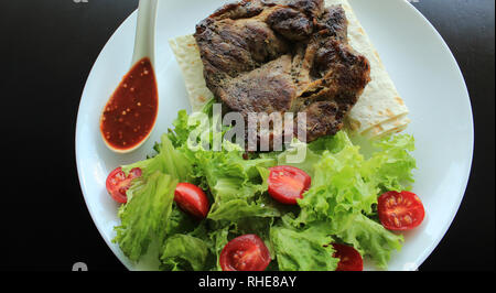 Gegrilltes Rumpsteak serviert mit Tomaten, Salat, Hot Sauce und dünne Fladenbrot Stockfoto