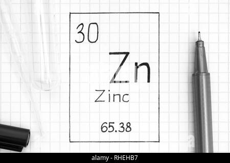 Das Periodensystem der Elemente. Handschrift chemisches Element Zink Zn mit schwarzem Stift, Reagenzglas und Pipette. Close-up. Stockfoto