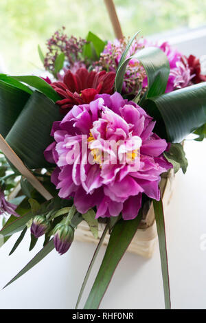 Strauß in einem Gelbstirn-blatthühnchen Korb mit einer wunderschönen Lilac Pfingstrose. Stockfoto