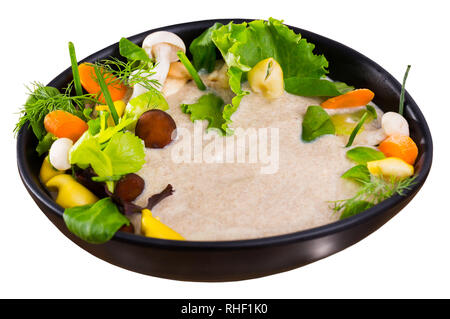 Leckere Cremesuppe mit verschiedenen Pilzen garniert mit geschnittene Karotten, Sellerie und Grüns, serviert mit Brot. Auf weissem Hintergrund Stockfoto