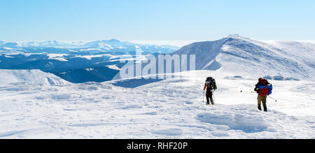 Zwei Touristen zu Fuß auf schneebedeckten Bergrücken in Richtung Gipfel. Der Himmel ist klar, sonnig. Winter. Die Ukraine Stockfoto