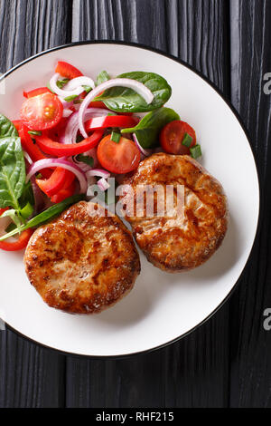 Lecker Frikadellen crepinette in einem ñaul Fett und frisches Gemüse Salat close-up auf einem Teller gewickelt. Vertikal oben Ansicht von oben Stockfoto