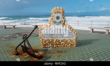 Eine Plakette in Portugiesisch Beschreibung stolz maritime Tradition neben ein Rostiger Anker der Stadt, mit Blick auf den Atlantik. Stockfoto