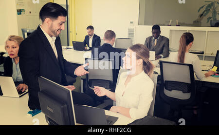 Gut aussehender bärtiger Mann reden und flirten mit attraktiven lächelnde Frau, die in co-Arbeitsbereich Stockfoto
